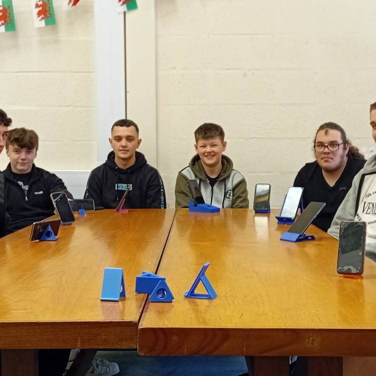 Myfyrwyr cwrs Diploma Estynedig BTEC mewn Peirianneg Gyffredinol yng Ngholeg Meirion-Dwyfor yn dangos eu standiau ar gyfer ffonau symudol