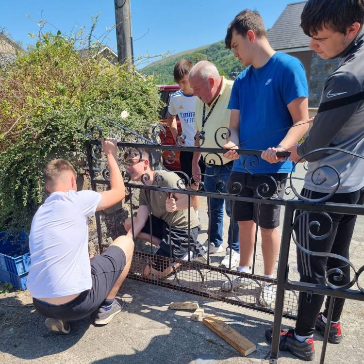 Myfyrwyr yn gosod y giât gyda Gwyn Williams yn gwylio