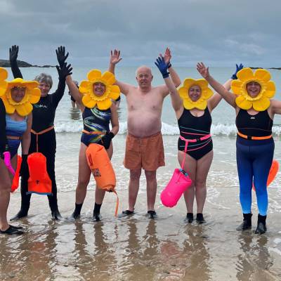 Criw o bobl ar draeth Bae Trearddur ar ôl nofio yn y môr yn ystod sesiwn Lluosi