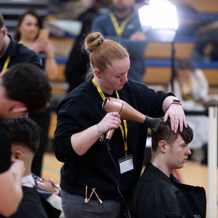 Leah Oldham, myfyriwr o Goleg Llandrillo, yn steilio gwallt yn rownd derfynol Dysgwr y Flwyddyn 2024 - Gwallt Cysyniadol